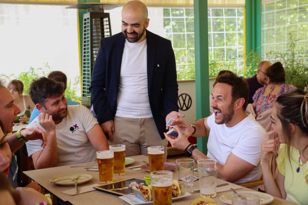 Mago para cumpleaños de adultos en Madrid Un grupo de adultos riéndose durante un juego de cartas en la sobremesa, alrededor de la mesa